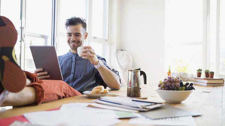 Man sitting at a table and reviewing his credit score on a tablet