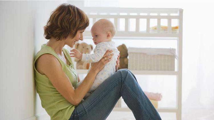 Mom sitting on the floor smiling and holding her baby